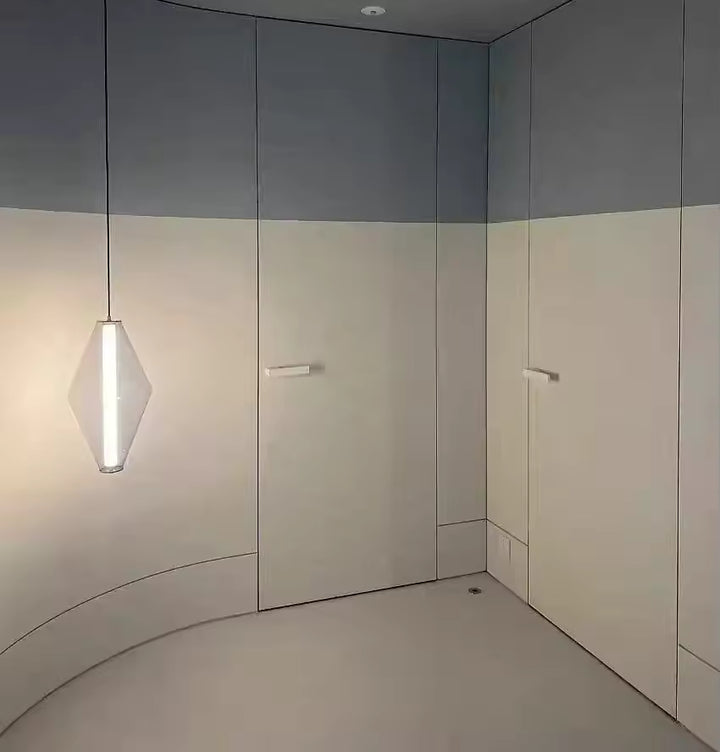 Suspension en verre facetté au design épuré, soulignée par une ligne lumineuse verticale dans un intérieur minimaliste