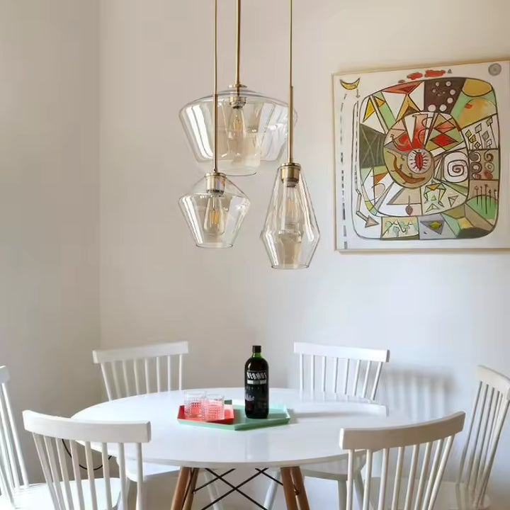 Suspension en verre géométrique et laiton au-dessus d’une table, dans une salle à manger d’inspiration rétro