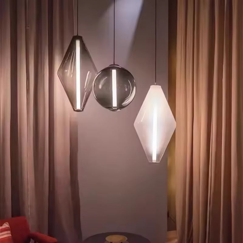 Trio de luminaires en verre aux formes géométriques et sphériques, éclairés par une fine ligne LED verticale