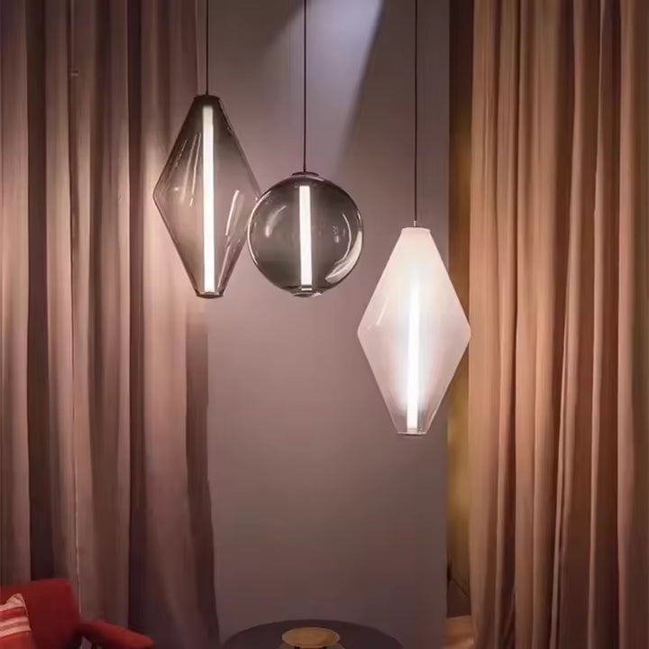 Trio de luminaires en verre aux formes géométriques et sphériques, éclairés par une fine ligne LED verticale