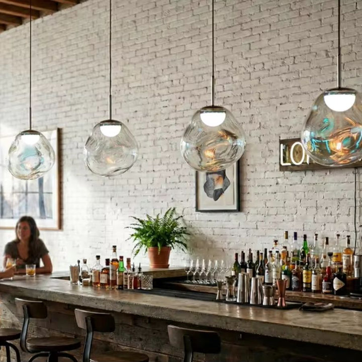 Suspension en verre irisé suspendue au-dessus d’un bar, avec globes lumineux au style loft industriel et design