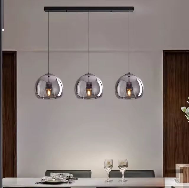 Suspension verre noir élégante au-dessus d’une table à manger, parfaite pour un intérieur moderne et convivial.