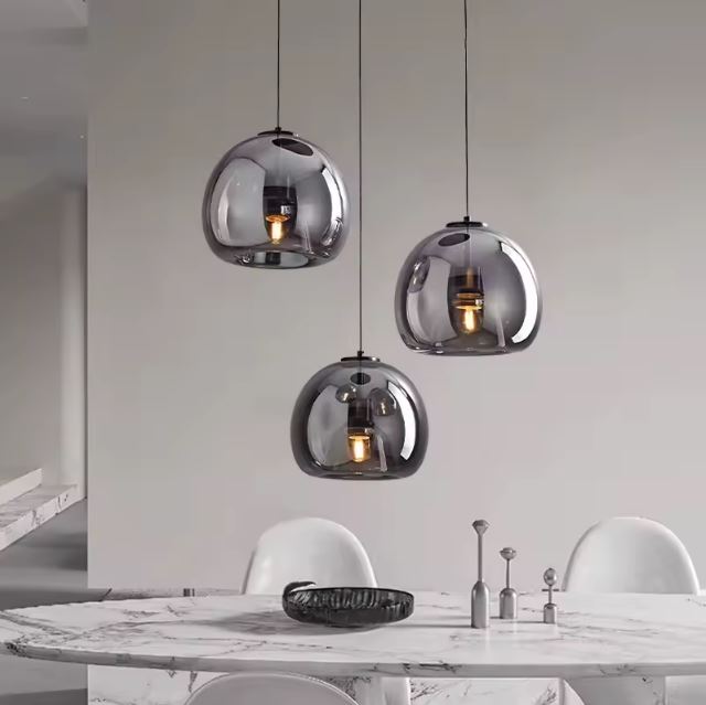 Suspension verre noir design en trio, suspendue au-dessus d’une table en marbre pour une ambiance chic et contemporaine.