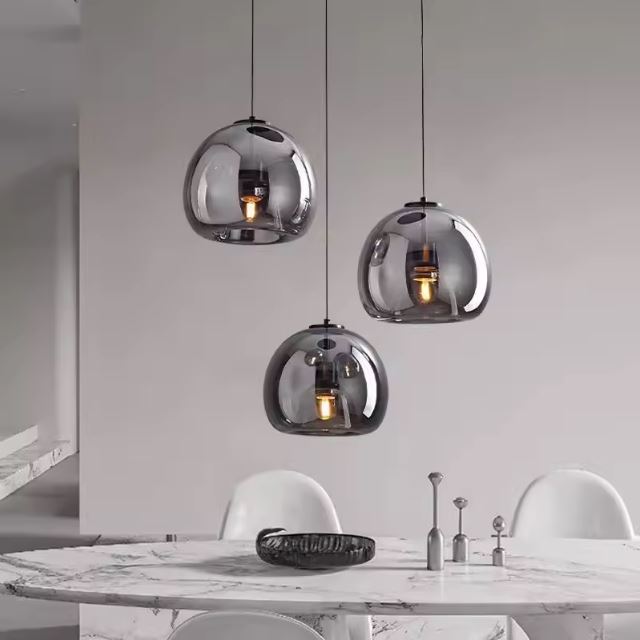 Suspension verre noir moderne à trois hauteurs, élégante au-dessus d’une table en marbre pour un style contemporain raffiné.