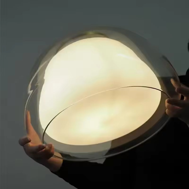 Détail d’une suspension en verre à cœur opalin lumineux, aux volumes arrondis et au design organique raffiné