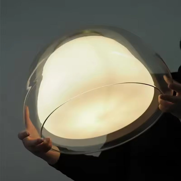 Détail d’une suspension en verre à cœur opalin lumineux, aux volumes arrondis et au design organique raffiné