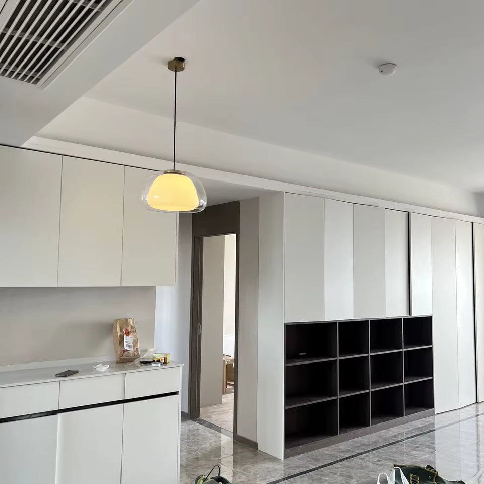 Dans un intérieur minimaliste, cette suspension en verre transparent et opalin apporte une lumière douce et contemporaine