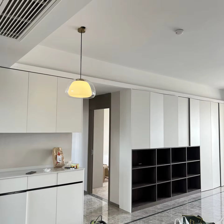 Dans un intérieur minimaliste, cette suspension en verre transparent et opalin apporte une lumière douce et contemporaine