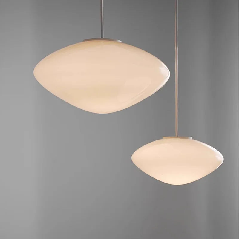 Suspension design en verre opalin blanc, idéale pour un éclairage doux et élégant au-dessus d'une table.