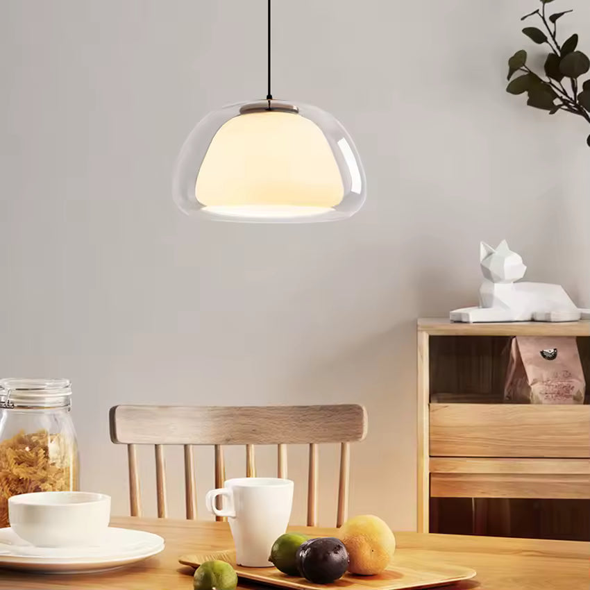 Éclairage suspendu en verre transparent et opalin au style scandinave doux dans une salle à manger en bois