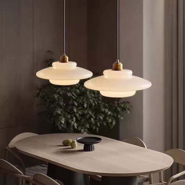 Suspensions modernes en verre opaline, parfaites pour illuminer une salle à manger avec élégance et sobriété.