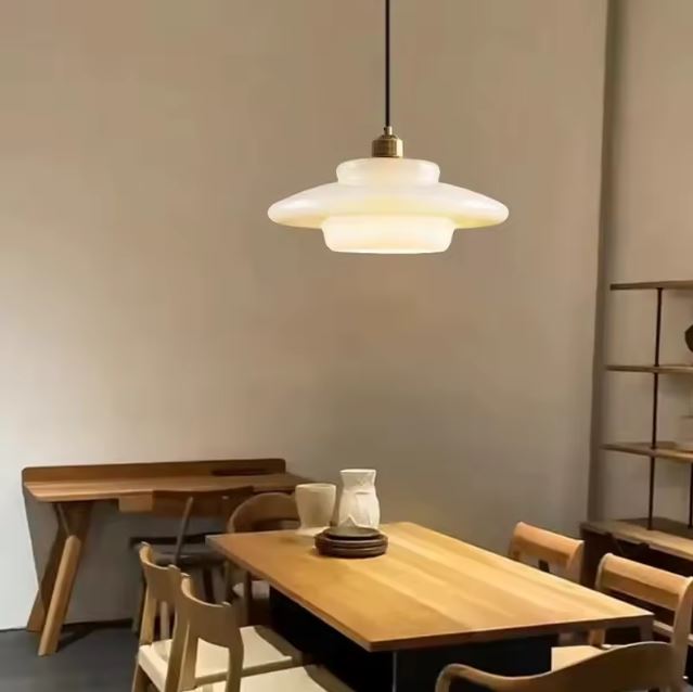 Suspension en verre opaline élégante illuminant une salle à manger moderne avec son éclairage doux et chaleureux.