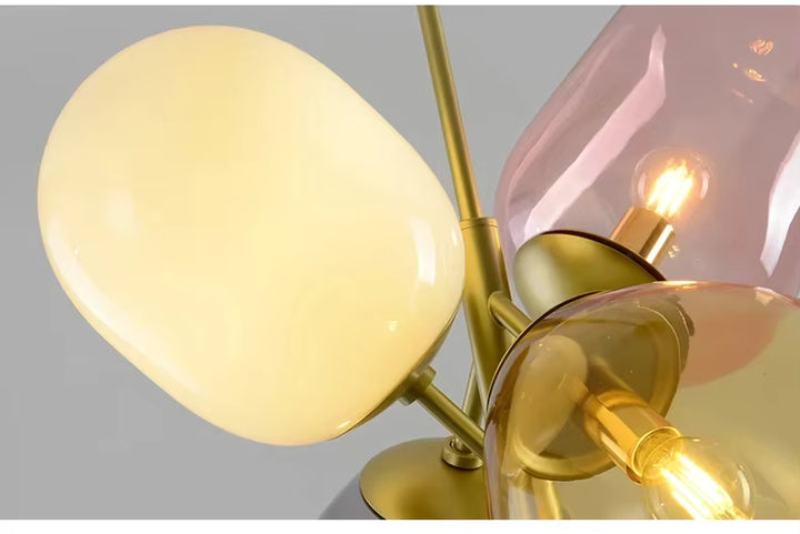 Gros plan sur les verres opalin, ambre et rose d’une suspension rétro aux accents vintage et à la structure dorée