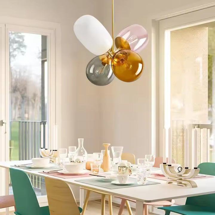 Suspension rétro à verres colorés ambre, fumé, rose et blanc dans une salle à manger au style scandinave