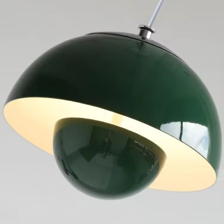 Vue rapprochée d’un luminaire suspendu vert profond à dôme et sphère, aux courbes rétro et à la finition brillante