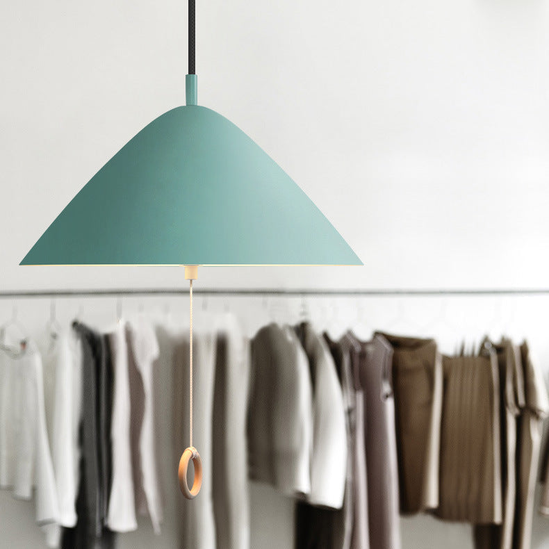 Suspension verte style danois éclairant un espace dressing avec étagères en bois.