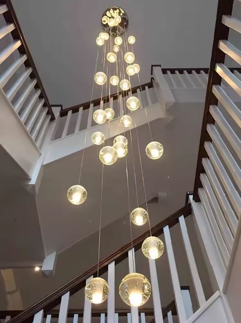Suspension verticale à globes en verre lumineux pour cage d’escalier moderne et plafond grande hauteur.