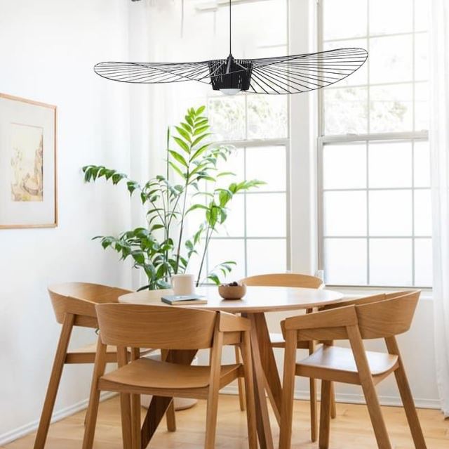 Suspension Vertigo noire, apportant une touche design et aérienne dans une salle à manger lumineuse au style naturel.