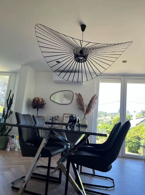 Suspension Vertigo noire au design graphique aérien, luminaire contemporain créant un fort impact visuel en salle à manger.