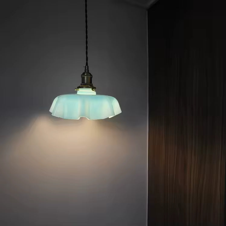 Abat-jour festonné bleu pâle suspendu dans une ambiance tamisée, au charme rétro doux et décoratif