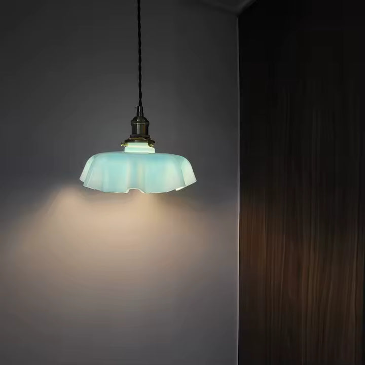 Abat-jour festonné bleu pâle suspendu dans une ambiance tamisée, au charme rétro doux et décoratif