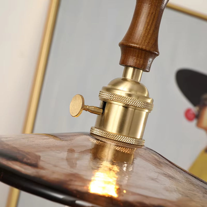 Détail de la finition en bois et laiton d’une suspension en verre ambré au style rétro sophistiqué