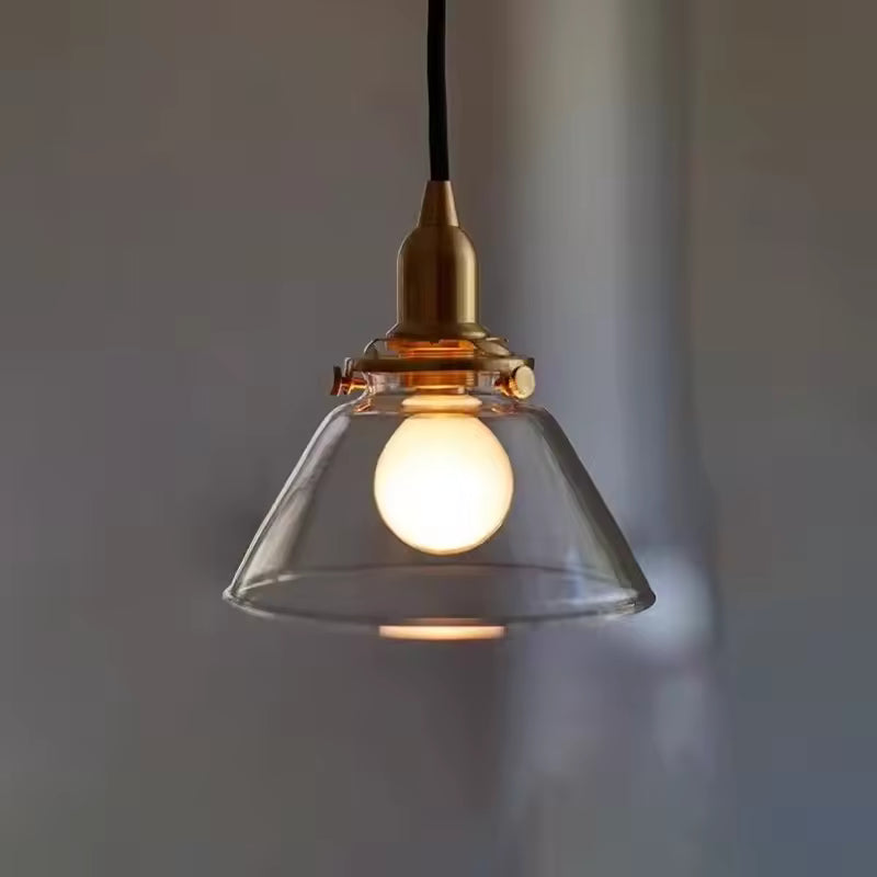 Sous une lumière chaude, suspension en verre cloche et laiton au style vintage sobre et élégant