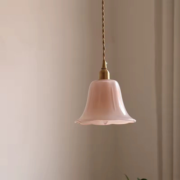 Suspendue près du lit, cette lampe en verre et laiton diffuse une lumière chaude au style vintage discret