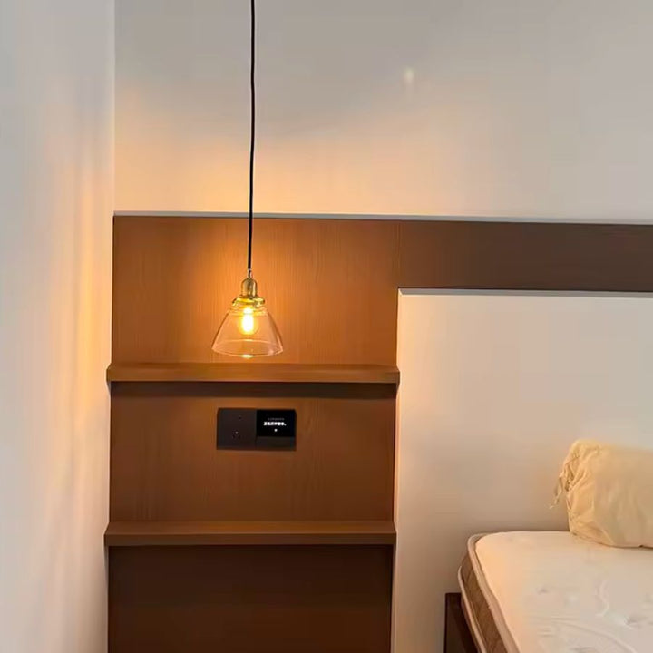 Suspendue près du lit, cette lampe en verre et laiton diffuse une lumière chaude au style vintage discret