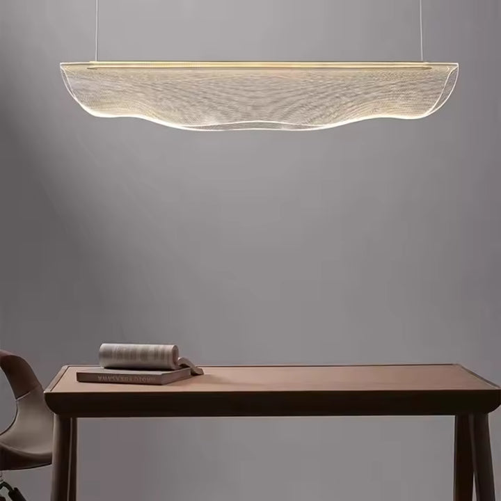 Suspension en acrylique lumineux en forme de voile ondulé, au style épuré et aérien au-dessus d’une table