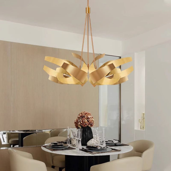 Suspension dorée à volutes entrelacées en métal suspendue au-dessus d'une table à manger dans un salon chic et lumineux.