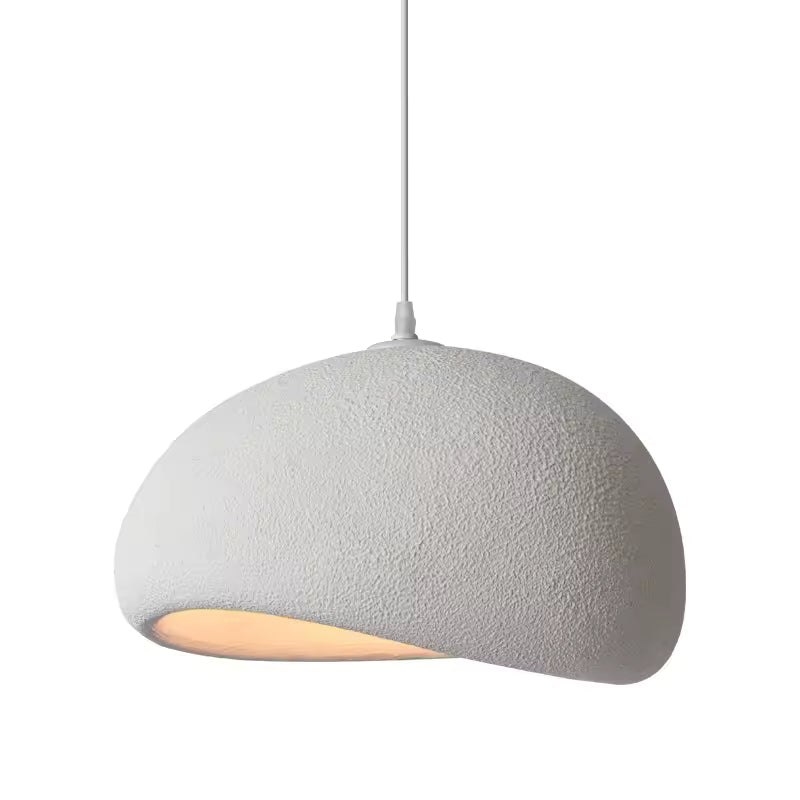 Vue rapprochée d'une suspension blanche sculpturale au dôme asymétrique, finition minérale texturée et lumière chaude.