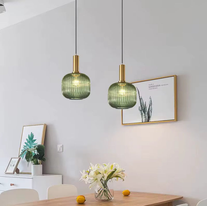 Suspension en verre cannele doree positionnee au-dessus d une table de repas, eclairage decoratif elegant creant une ambiance chaleureuse et conviviale dans la salle a manger