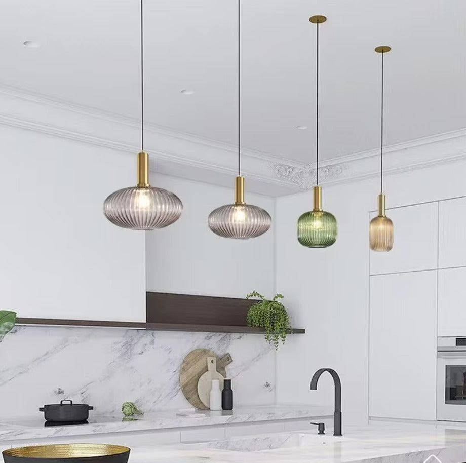 Suspension en verre cannele doree installee au-dessus d un ilot de cuisine, luminaire decoratif apportant une lumiere chaleureuse et une touche elegante a un interieur moderne