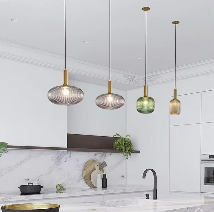 Suspension en verre cannele doree installee au-dessus d un ilot de cuisine, luminaire decoratif apportant une lumiere chaleureuse et une touche elegante a un interieur moderne