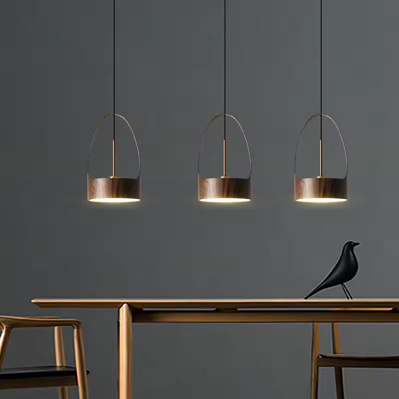 Trois suspensions à arche métallique effet bois diffusent une lumière douce dans un intérieur moderne et épuré