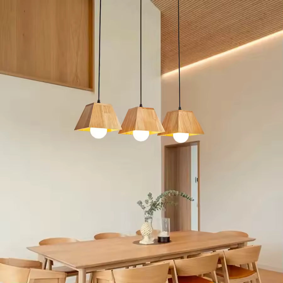 Trois suspensions géométriques en bois à globe opalin au-dessus d’une table, dans une salle à manger japandi et épurée
