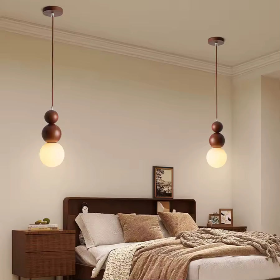 Deux suspensions en bois à globe opalin encadrant le lit, dans une chambre douce au style scandinave et naturel