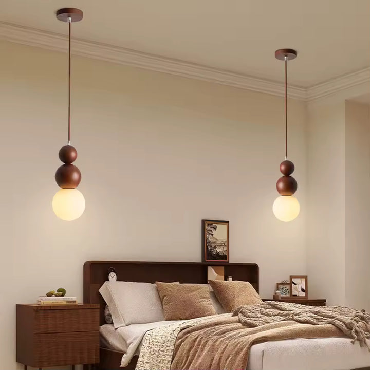Deux suspensions en bois à globe opalin encadrant le lit, dans une chambre douce au style scandinave et naturel