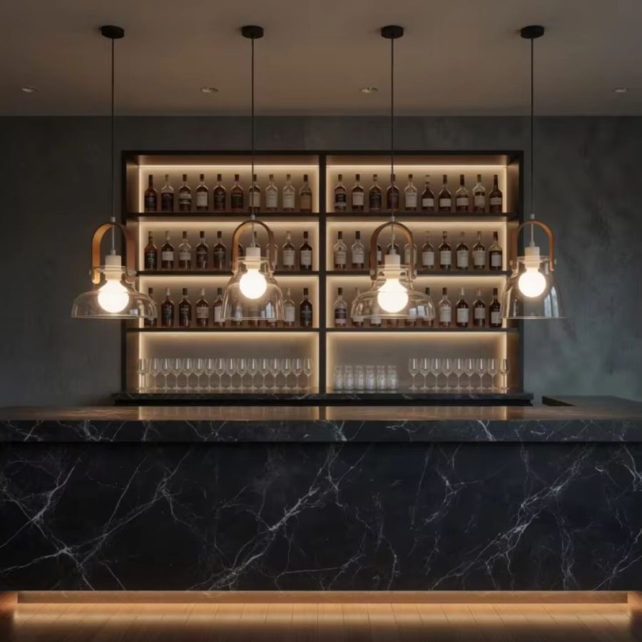 Quatre suspensions en bois et verre soufflé rythment un bar en marbre noir dans une ambiance élégante et contemporaine