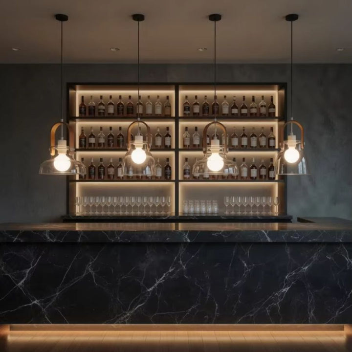Quatre suspensions en bois et verre soufflé rythment un bar en marbre noir dans une ambiance élégante et contemporaine
