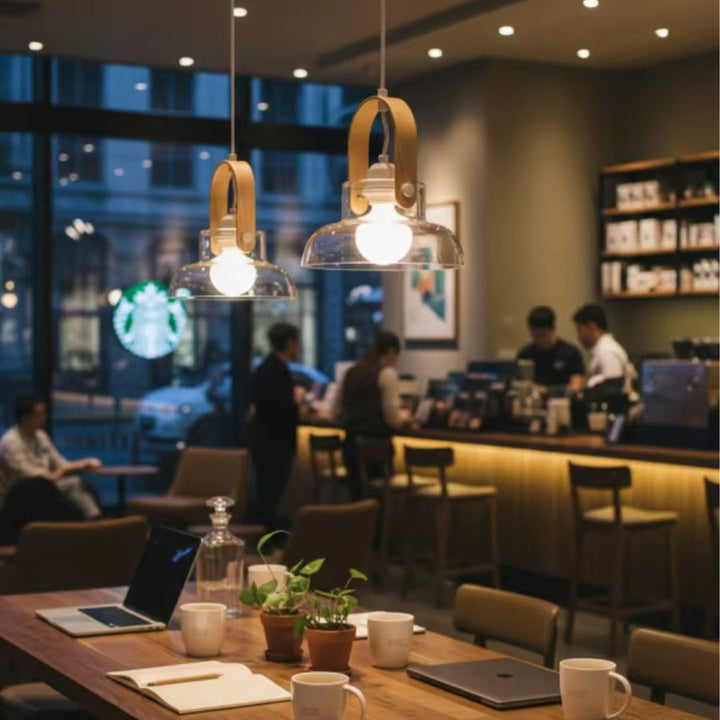 Deux suspensions en bois clair et verre soufflé éclairent une table de café dans une ambiance contemporaine chaleureuse