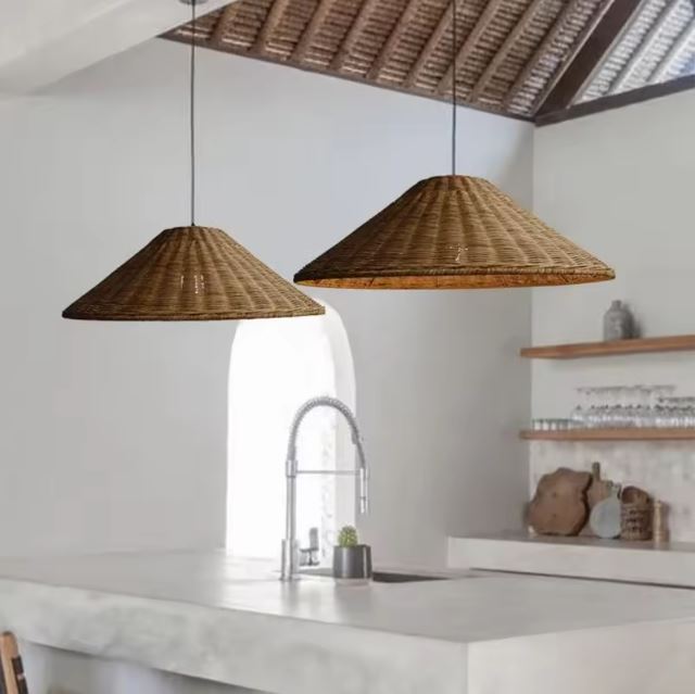 Duo de suspensions chapeau en rotin naturel illuminant une cuisine moderne avec un îlot central en béton.