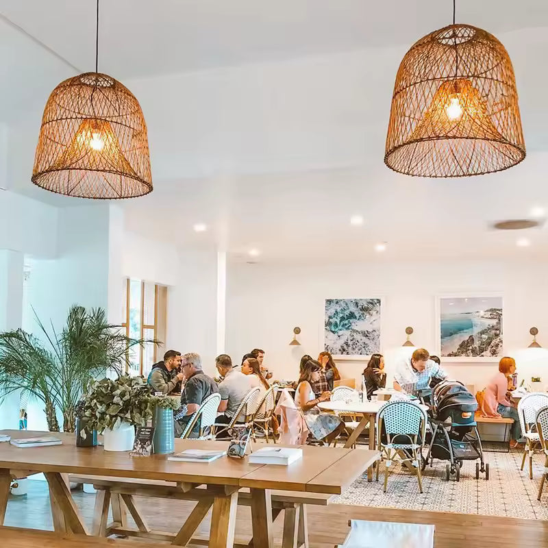 Deux suspensions en rotin tressé à double abat-jour diffusent une lumière douce dans un restaurant au style bohème côtier.