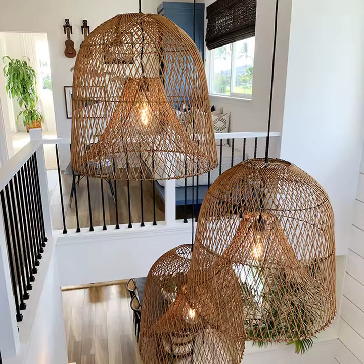 Trois suspensions en rotin naturel à double abat-jour ajouré, disposées en cascade dans une cage d'escalier lumineuse.