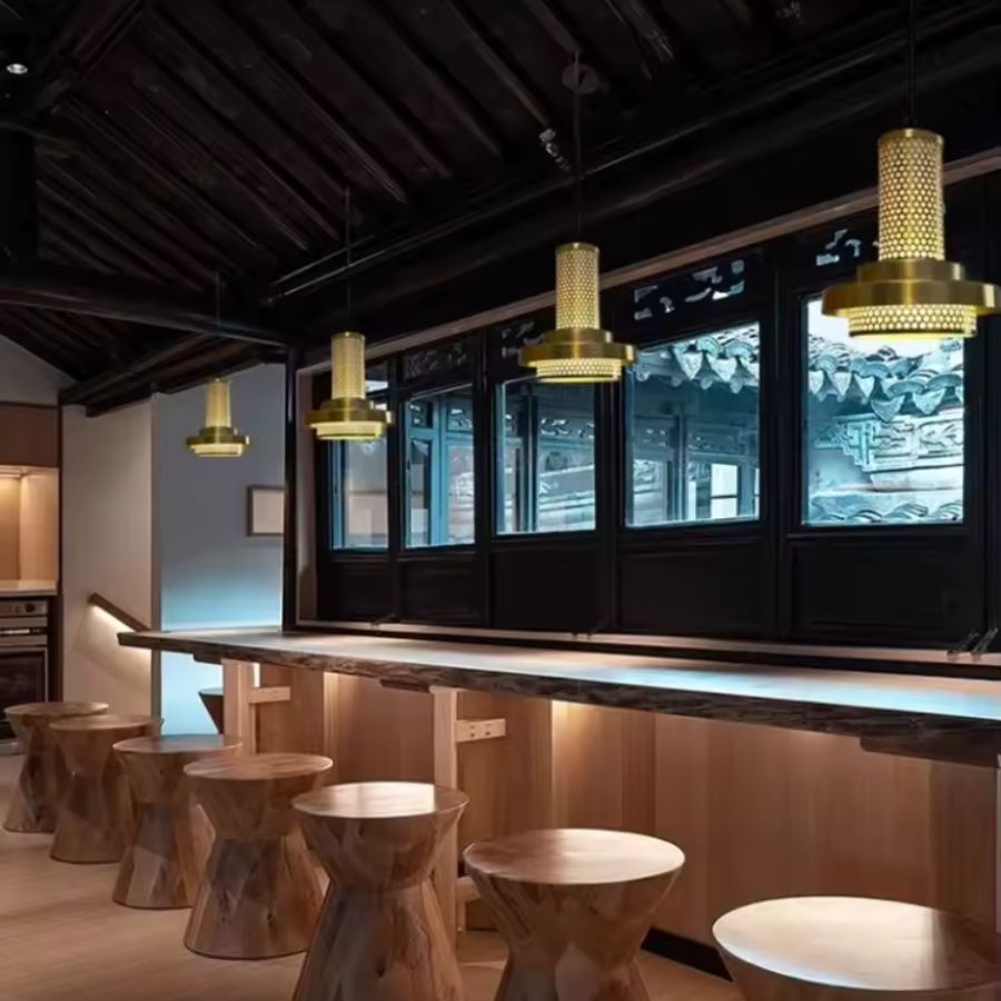 Alignées au-dessus d’un comptoir en bois, ces suspensions dorées à colonne ajourée affichent un style rétro design