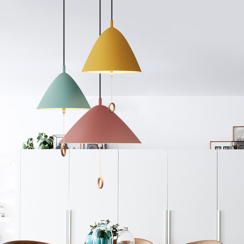 Grappe de suspensions colorées style danois au-dessus d'une table ronde en bois.