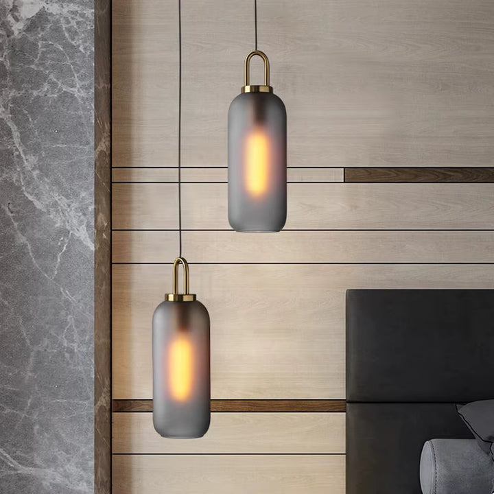 Duo de suspensions cylindriques en verre fumé à anse dorée dans une chambre au style chic et contemporain