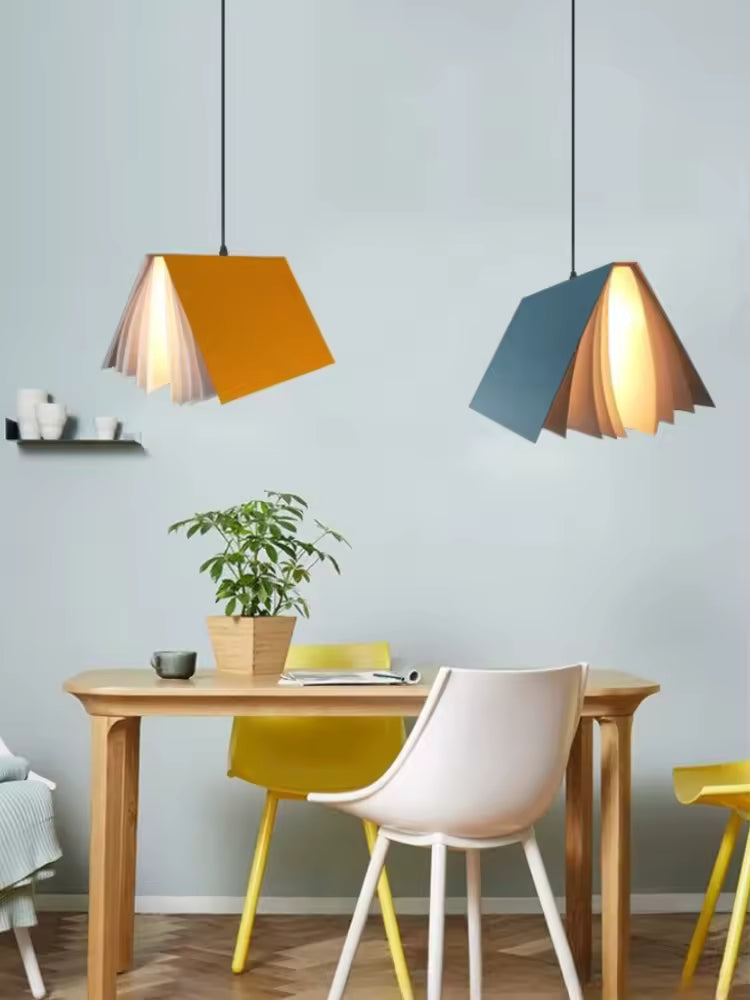 Deux suspensions design en forme de livre ouvert colorées, dans une salle à manger moderne à l’esprit créatif