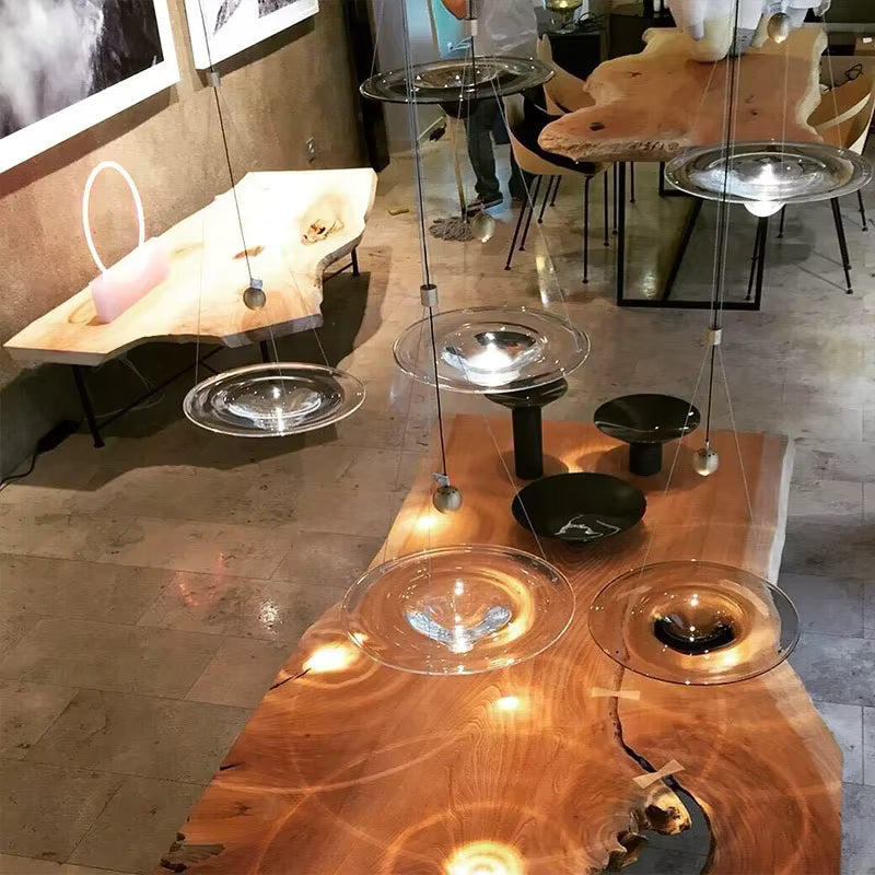 Plusieurs suspensions disque en verre à cœur goutte animent un intérieur design avec reflets lumineux sophistiqués